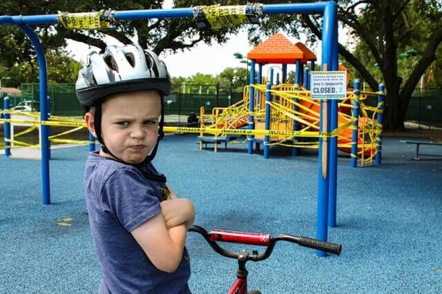 Kind mit Helm ist frustriert vor Spielplatz