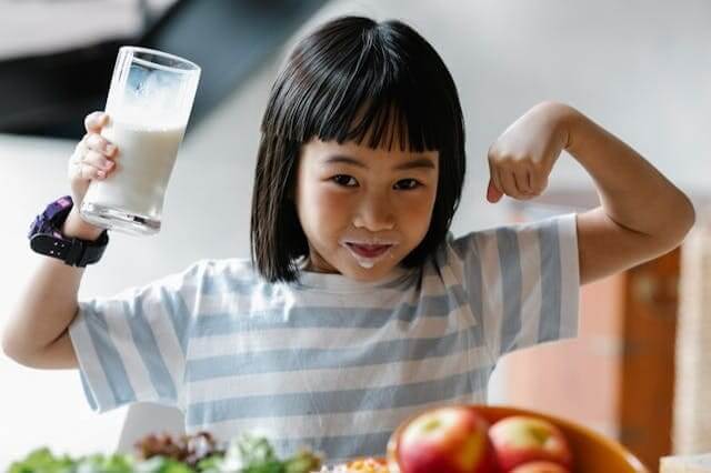 Kind trinkt Milch beim Essen